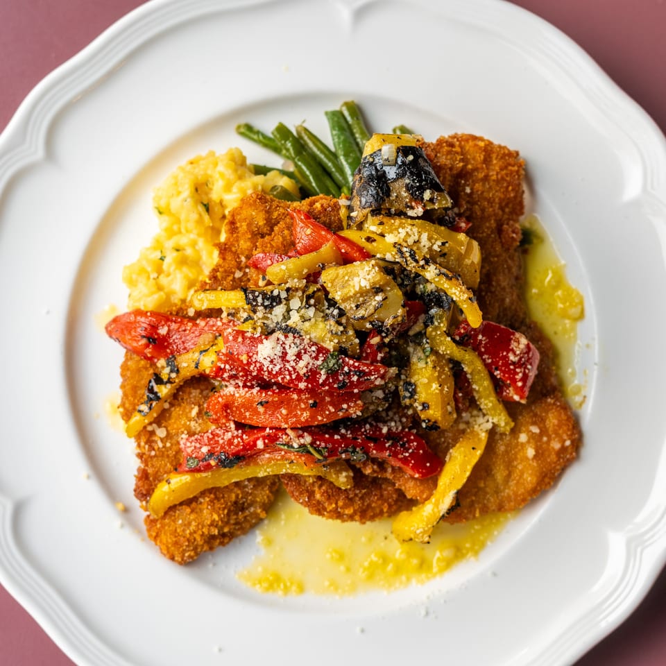 Crispy breaded cutlets topped with roasted red and yellow peppers, eggplant, green beans, and creamy mashed potatoes.