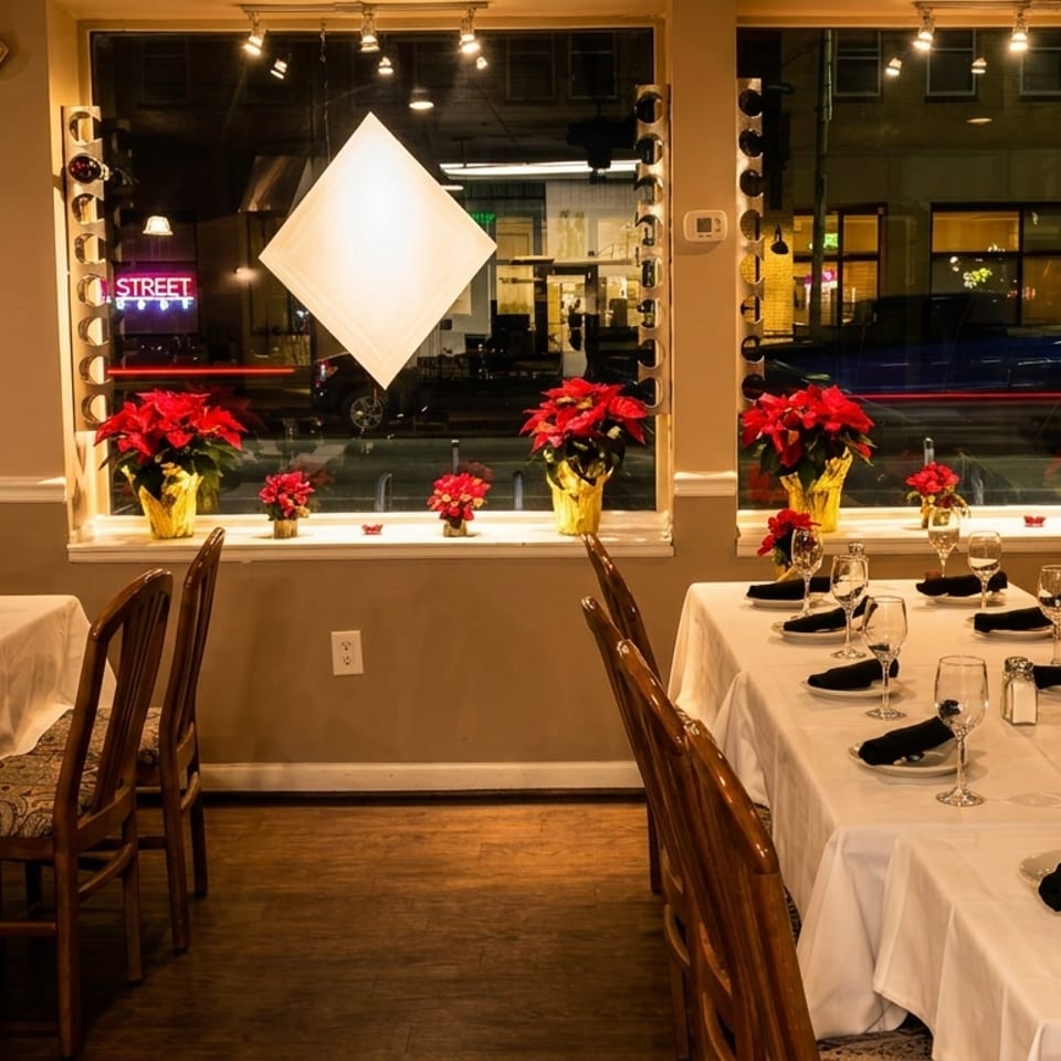 Restaurant dining room with set tables, poinsettia decorations, and large windows overlooking a street.